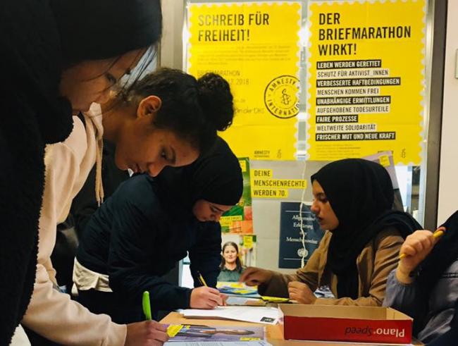 Eine Schülerin unterschreibt einen Brief für Menschenrechte